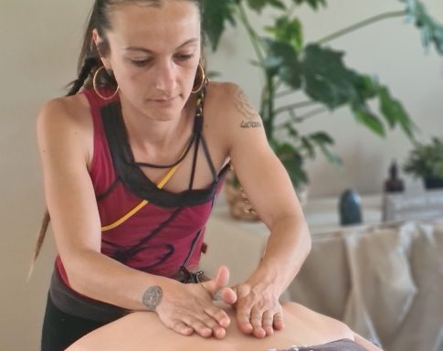 Femme massant le dos d'une personne sur une table de massage, ambiance apaisante.